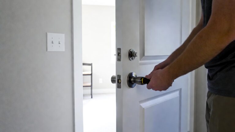 Swapping builder-grade hardware — A bright, inviting interior door partially open showing a modern, stylish door handle being installed by a homeowner using a screwdriver, with new matching switch plates and light fixtures visible in the background, conveying a fresh home upgrade vibe.